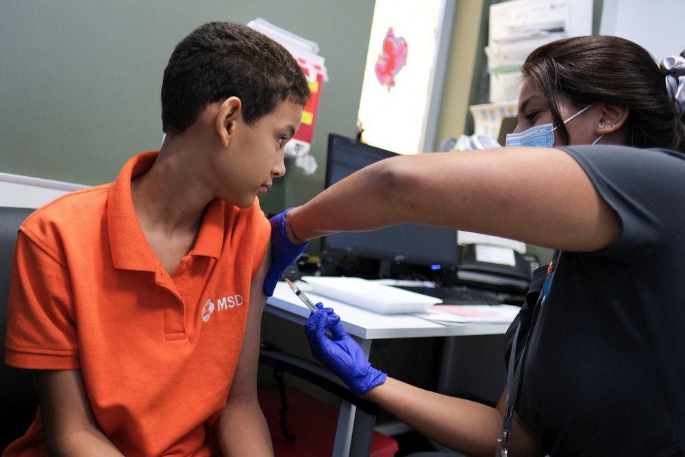 Young boy receives vaccine in arm from nurse