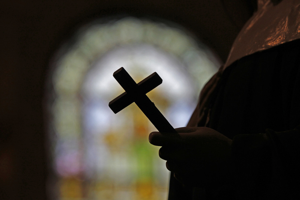 Image of a crucifix silhouetted against a stained glass window. 