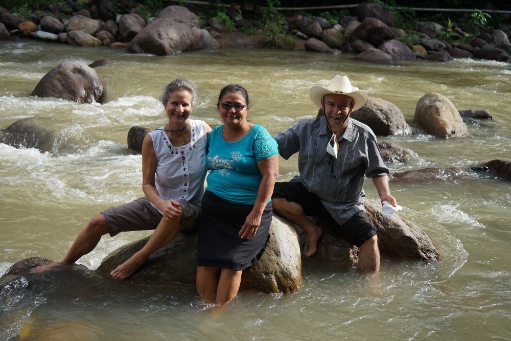 Mary Anne Perrone, left, and Jose Artiga, right, enjoy the Guapinol River with a community member. Perrone and Artiga led the SHARE delegation intended to bring international attention to issues in Honduras. (SHARE Foundation/Mark Coplan)