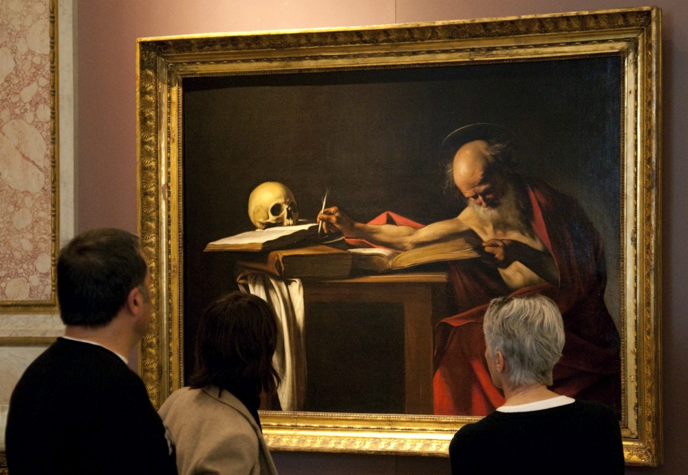 Visitors are pictured in a file photo looking at a Caravaggio painting titled "St. Jerome Writing" during an exhibition at the Galleria Borghese in Rome. Pope Francis released an apostolic letter on the Bible Sept. 30. (CNS/Reuters/Max Rossi)