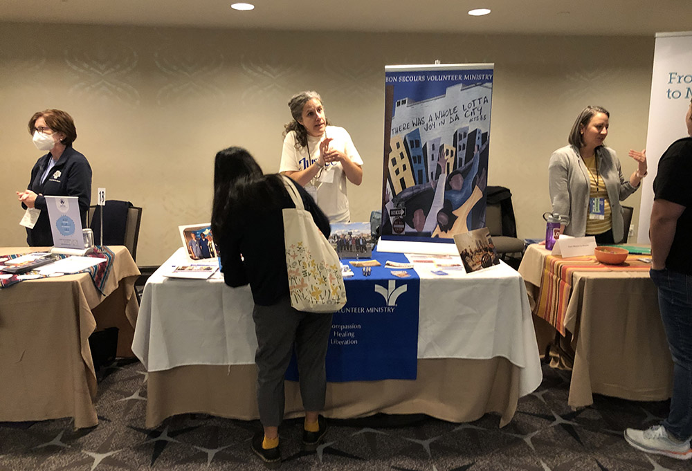 Emily Thrush, site leader for Bon Secours Volunteer Ministry in Richmond, Virginia, talks with Bianca Widjaja at the Bon Secours Volunteer Ministry table at the Ignatian Family Teach-In for Justice in Washington, D.C., Oct. 23. (NCR photo/Aleja Hertzler-McCain)