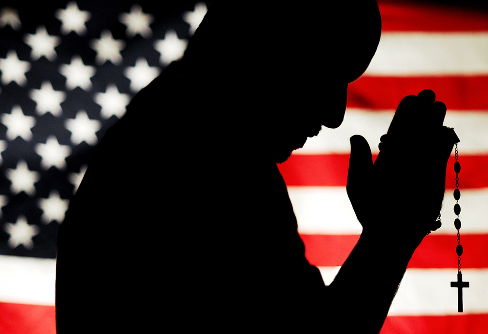 A man holding a rosary with the U.S. flag as a backdrop is silhouetted in this photo illustration. (CNS illustration/Catholic Courier/Mike Crupi)