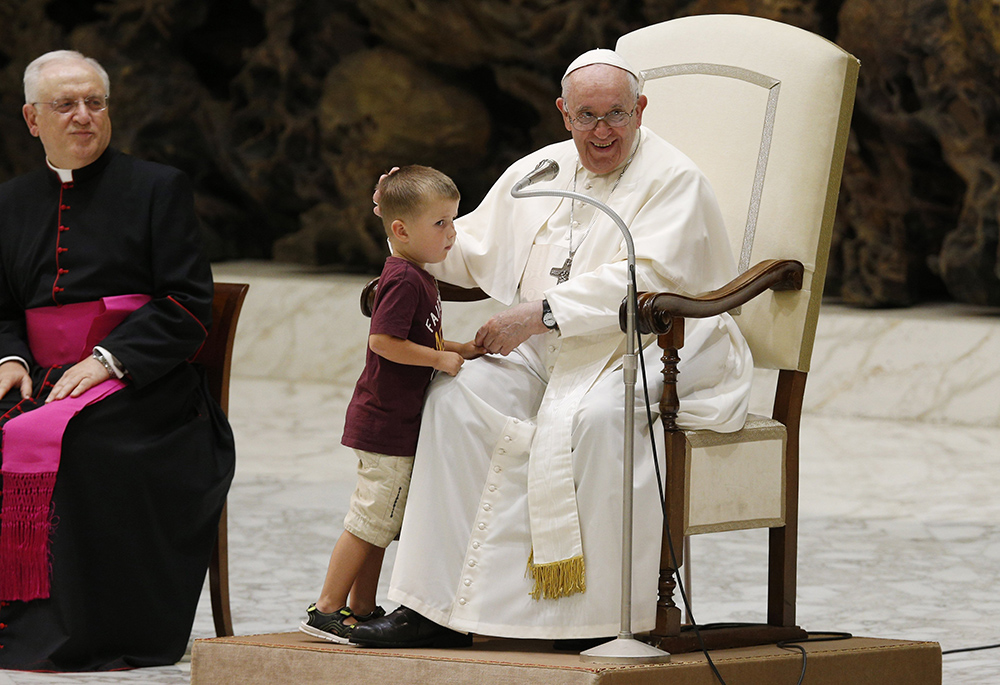 Pope Francis greets a boy who ran onstage during his general audience in the Paul VI hall Aug. 17, 2022, at the Vatican. (CNS/Paul Haring)