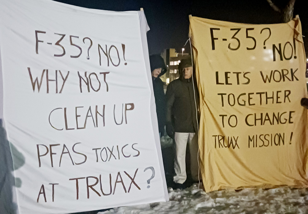 Participants in the Midwest Catholic Worker Faith and Resistance retreat hold up signs protesting the F-35 fighter jet outside Truax Field Air National Guard Base northeast of Madison, Wisconsin, on March 27. (NCR photo/Theodore Kayser)