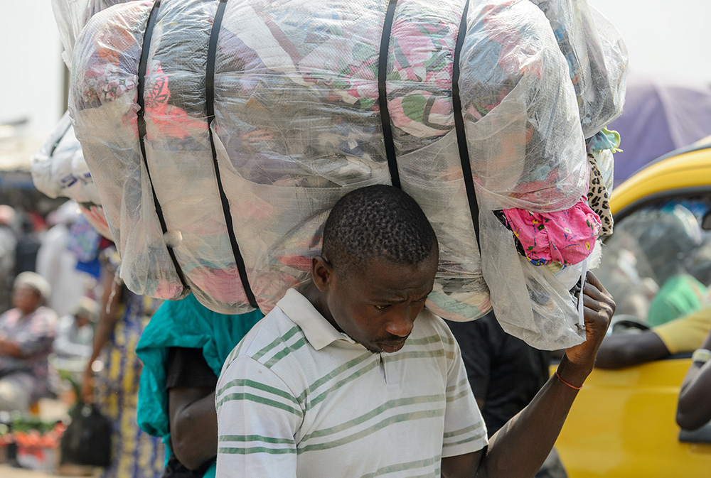 A man carries a bundle of clothing at the market in Kumasi, Ghana, Jan. 15, 2017. (Dreamstime/Siempreverde22)