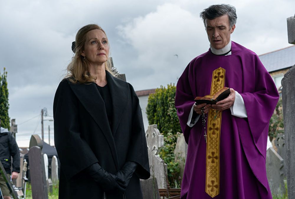 Laura Linney as Chrissie prepares to bury her mother alongside Mark O'Halloran as Fr. Dermot Byrne in "The Miracle Club." She later joins the pilgrimage to Lourdes. (Courtesy of Sony Pictures Classics/Jonathan Hession) 