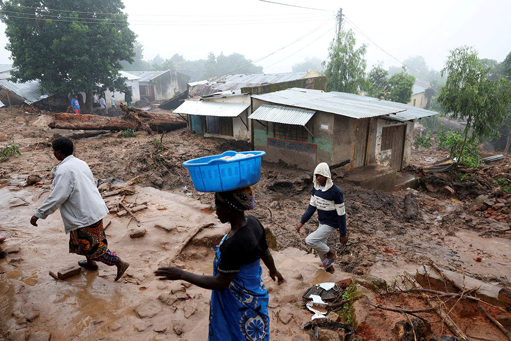 In Blantyre, Malawi, on March 17, people walk past houses that were damaged in the aftermath of Cyclone Freddy. (OSV News/Reuters/Esa Alexander)