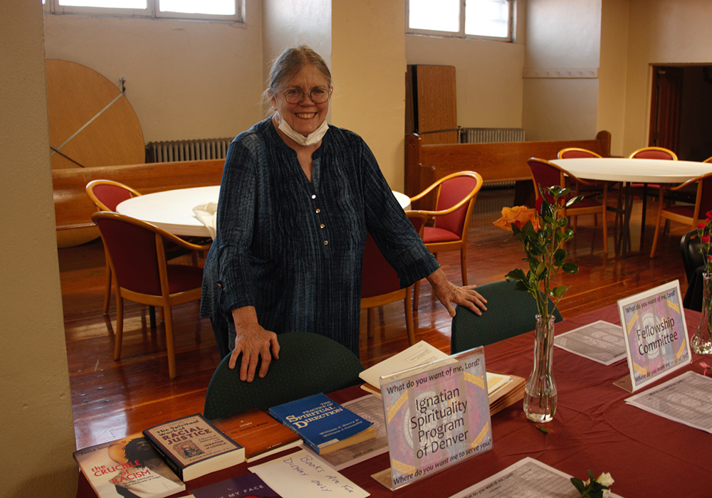 Mary McEnany, a spiritual director for the Ignatian Spirituality Program of Denver, stands at a table at St. Ignatius of Loyola Parish's 2022 Annual Ministry Fair. (Courtesy of Allan Rowley)