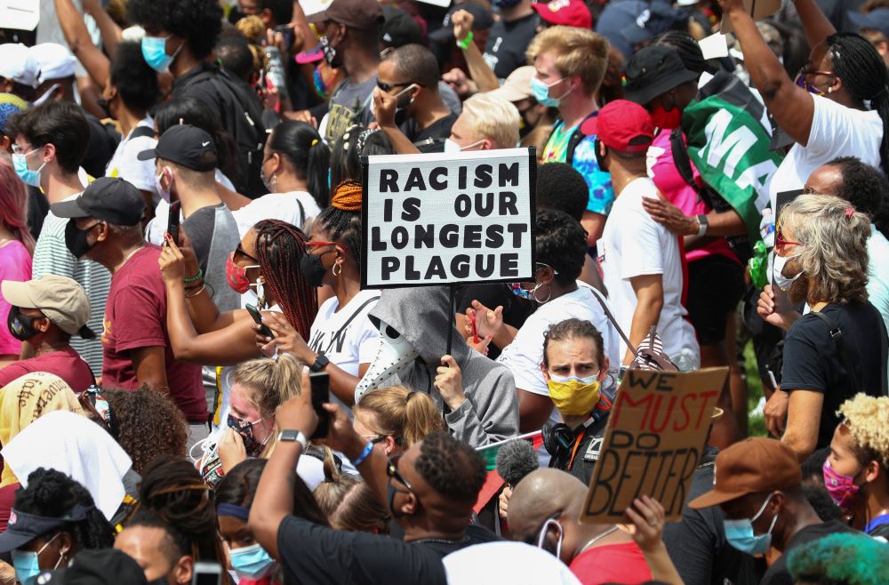 Protesters stand with a sign reading "Racism Is Our Longest Plague" in Washington Aug. 28, 2020, during the "Get Your Knee Off Our Necks" Commitment March on Washington 2020 in support of racial justice. 