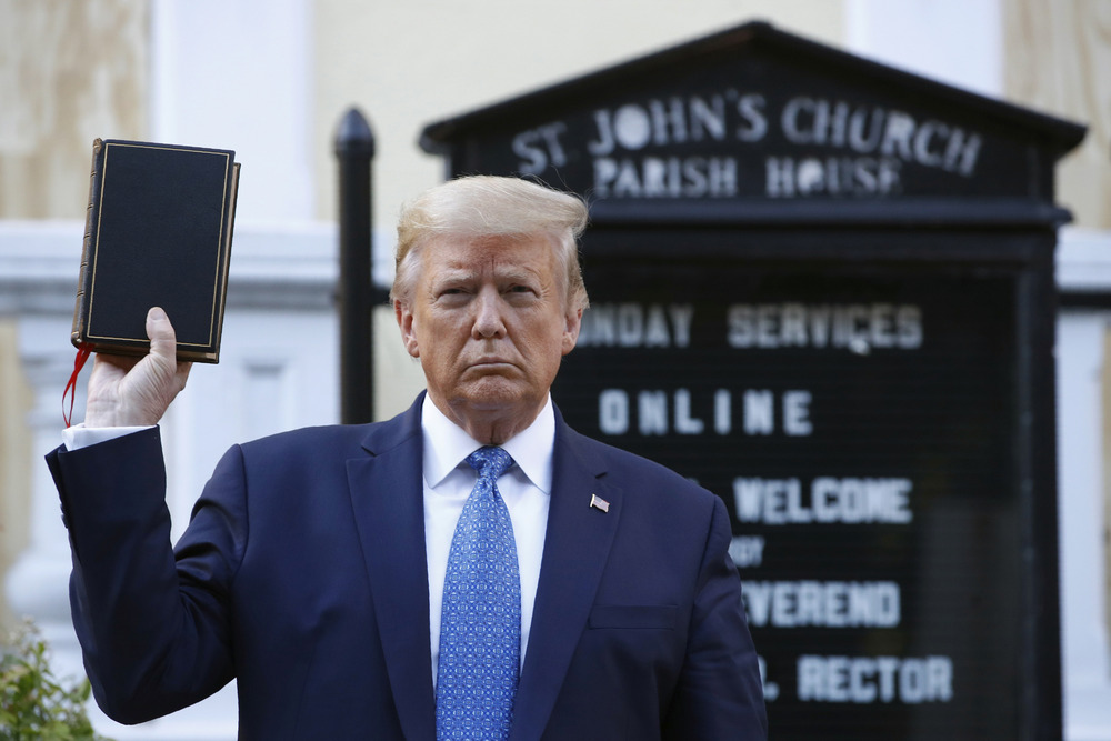 Donald Trump holds bible inf front of church sign.