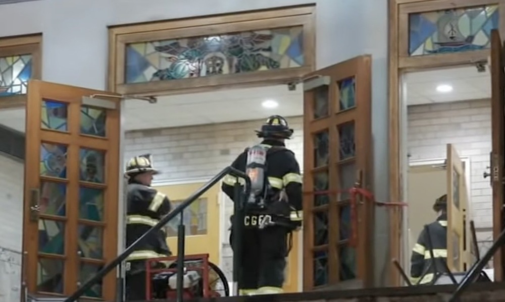 Firefighters seen through open doors of church. 