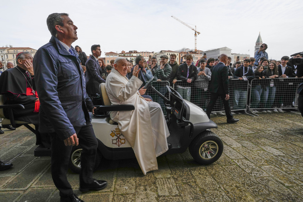 Pope Francis sits in mini popemobile and waves to people