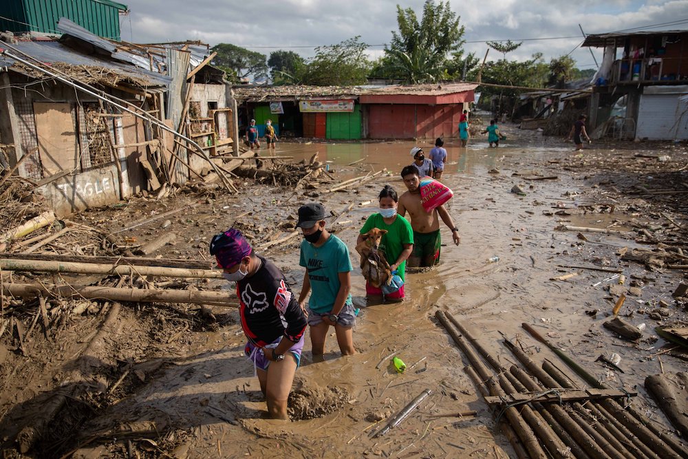 Residents wade through mud in Manila, Philippines, after Typhoon Vamco in 2020. (CNS photo/Eloisa Lopez, Reuters)
