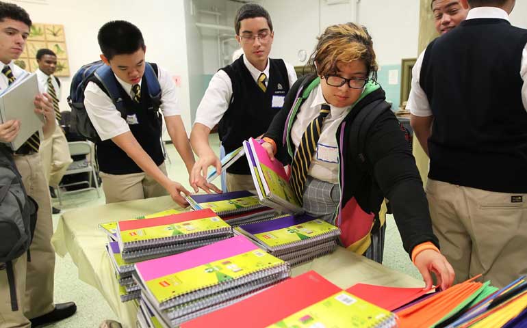 Kianna Cruz, center, a new student at Cristo Rey Philadelphia High School, picks out two notebooks that are provided by the school, along with other supplies, in August 2012. (AP/The Philadelphia Inquirer/Michael Bryant)