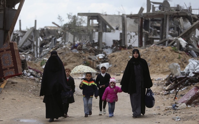In February 2015, Palestinians walk near the ruins of houses that witnesses said were destroyed or damaged by Israeli shelling during a 50-day war in the summer of 2014, near Gaza City. (CNS/Ibraheem Abu Mustafa, Reuters)