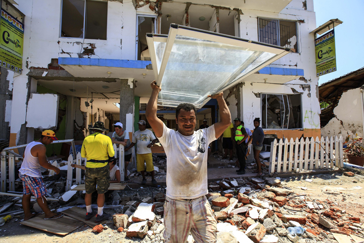 Residents recover some of their belongings April 25 from debris of a destroyed building in Canoa, Ecuador. (CNS/Jose Jacome, EPA, Reuters)