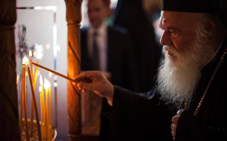 Orthodox Archbishop Ieronymos II lights a candle as he enters St. Mena Cathedral in Heraklion, Greece, June 19, 2016. (CNS/Sean Hawkey, handout)