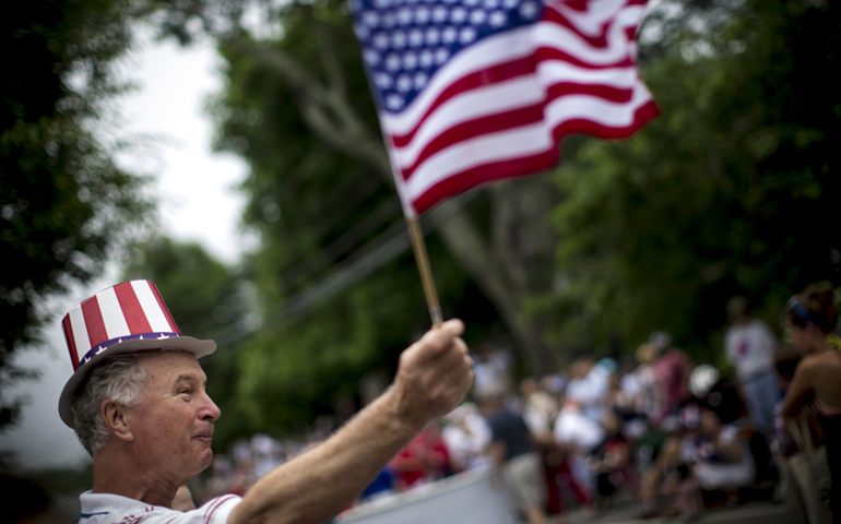 A man waves an American flag as he watches a Fourth of July parade in the village of Barnstable, Mass., on July 4, 2014. (RNS/Reuters/Mike Segar)
