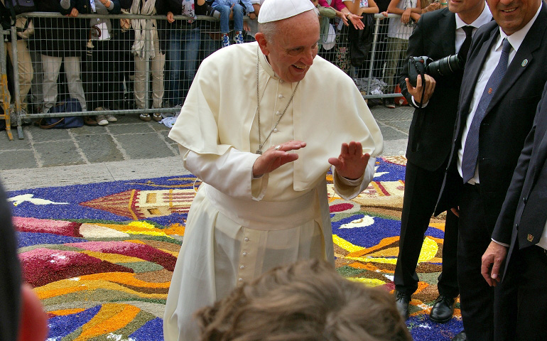 Pope Francis greets people outside Assisi's Cathedral of San Rufino on Oct. 4 before heading inside to speak to members of the cathedral and diocese's pastoral staff. Behind him are flowers arranged by participants of the 'Le infiorate' festival. The pope refused to walk on the flower carpet. (NCR photo/Joshua J. McElwee)