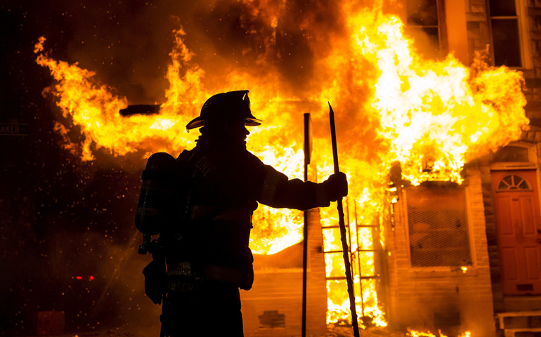 A Baltimore firefighter fights a fire at a convenience store and residence April 28 during clashes in response to the death of Freddie Gray. (CNS/Reuters/Eric Thayer)