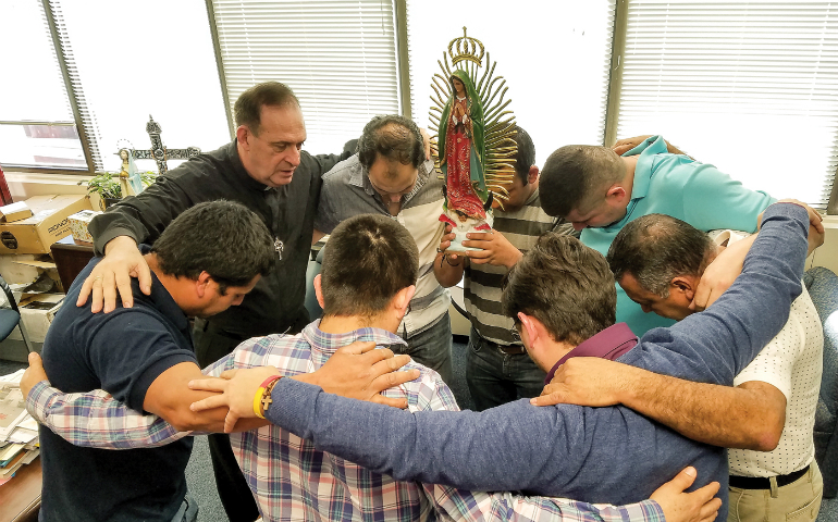 Fr. Jose E. Hoyos, director of the Spanish Apostolate Office of the Arlington diocese prays with a group of Hispanic leaders in his office Feb. 24. (CNS photo/Mary Stachyra Lopez, Arlington Catholic Herald) 