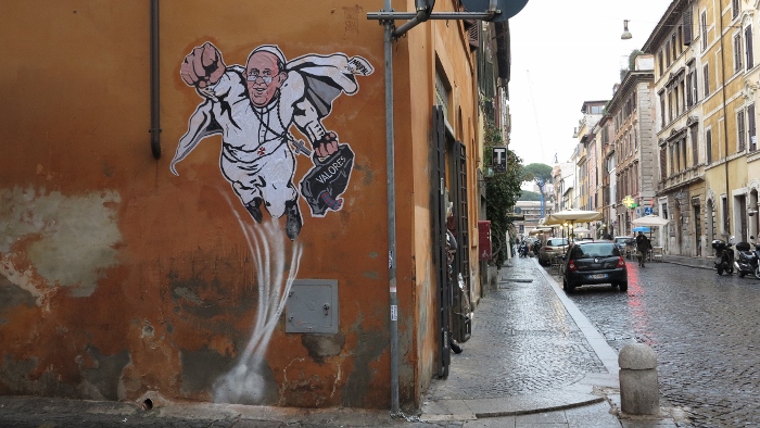 A large drawing of Pope Francis depicting him as a superhero is seen on a wall near the Vatican Jan. 29, 2014. The Argentine pope is shown taking off into the air with his right fist clenched in a classic Superman style. (CNS photo/Robert Duncan) 