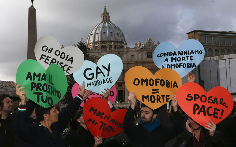 Members of a gay activist group hold up signs Dec. 16 outside St. Peter's Square at the Vatican. They demonstrated against part of Pope Benedict XVI's World Peace Day message, in which he affirmed Catholic teaching on marriage as the lifelong bond of a man and a woman. (CNS/Reuters/Alessandro Bianchi)