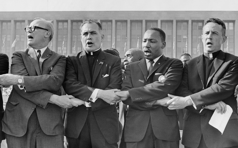 Holy Cross Fr. Theodore Hesburgh, second from left, joins hands with the Rev. Edgar Chandler, the Rev. Martin Luther King Jr., and Msgr. Robert Hagarty of Chicago in 1964 at the Illinois Rally for Civil Rights in Chicago's Soldier Field. (CNS/courtesy University of Notre Dame)