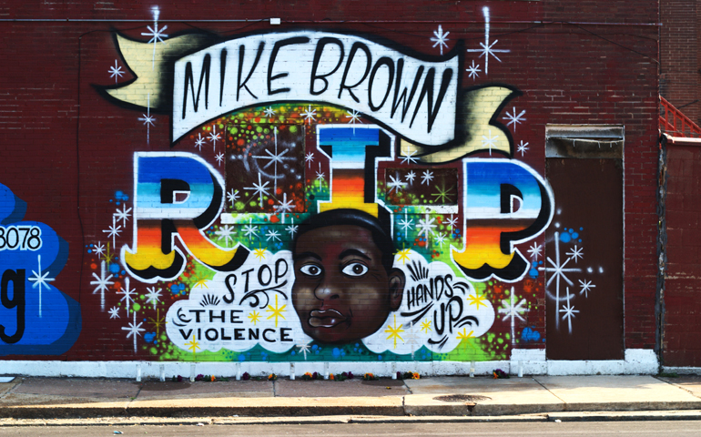 Candles and flowers sit in front of a mural honoring Michael Brown on the wall of a north St. Louis screen printing business. (NCR Photo/Robyn Haas)