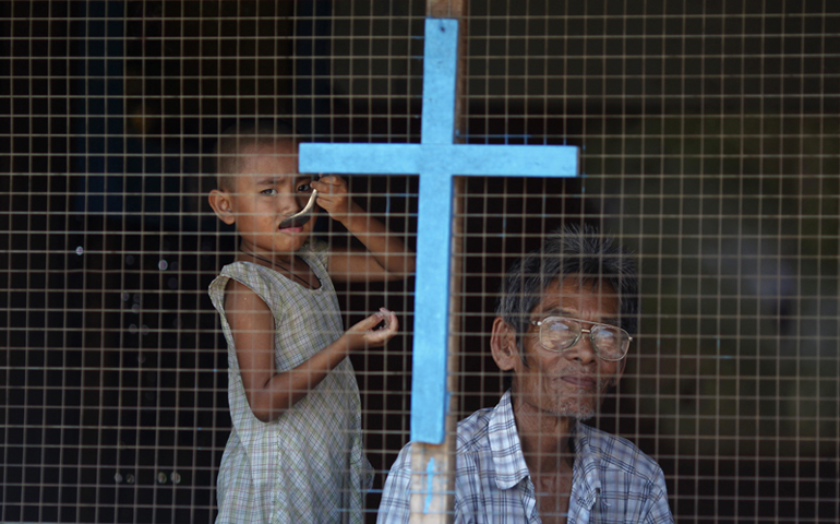 A man and a child from a Christian family look out from their home in the industrial suburbs of Yangon on April 14, 2012. (RNS/Reuters/Damir Sagolj)