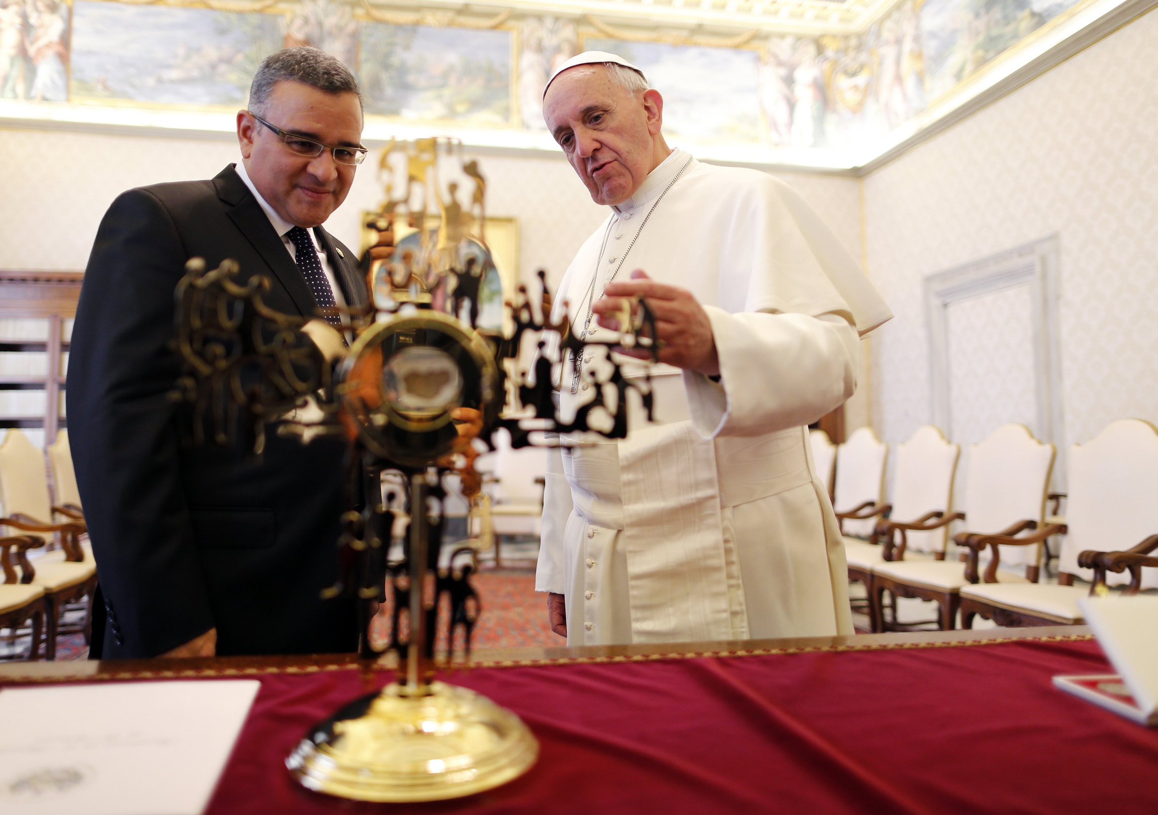 Pope Francis and President Mauricio Funes Cartagena of El Salvador look at a reliquary containing a blood-stained piece of the vestment of slain Archbishop Oscar Romero during a private audience in the Apostolic Palace at the Vatican May 23. (CNS photo/Alessandro Bianchi, Reuters)