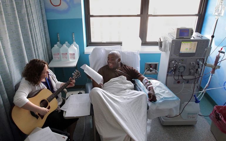 Akron Children's Hospital music therapist Sarah Tobias plays music with dialysis patient Chris Blackwell, 19, in May 2013 in Akron, Ohio. (MCT/Akron Beacon Journal/Phil Masturzo)