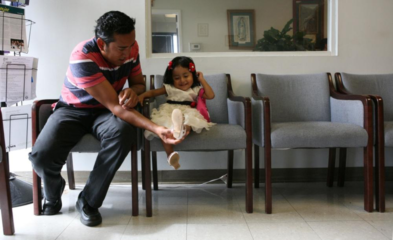 Fabian Martinez of Chiapas, Mexico, entertains his daughter, Nicole Martinez, 2, while they wait for his wife, Maresa Gutierrez who is consulting with an immigration attorney at Guadalupan Multicultural Services' La Casita in Birmingham, Alabama. (GSR/Nuri Vallbona)