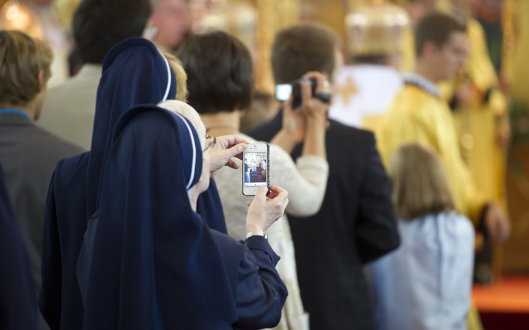 A nun records a video with her phone during the Divine Liturgy at Sts. Volodymyr and Olha Cathedral Sept. 9 in Winnipeg, Manitoba. (CNS/David Lipnowski) 