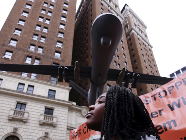 A woman listens to speakers below a model of a drone at a demonstration to protest overseas wars the United States is involved in and actions of U.S. Republican presidential candidate Donald Trump in New York on March 13, 2016. (Reuters/Lucas Jackson)