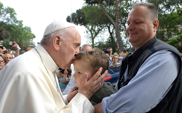 Pope Francis kisses a child as he arrives to bless houses during his visit to Ostia, on the outskirts of Rome, on May 19, 2017. (Osservatore Romano via Reuters)