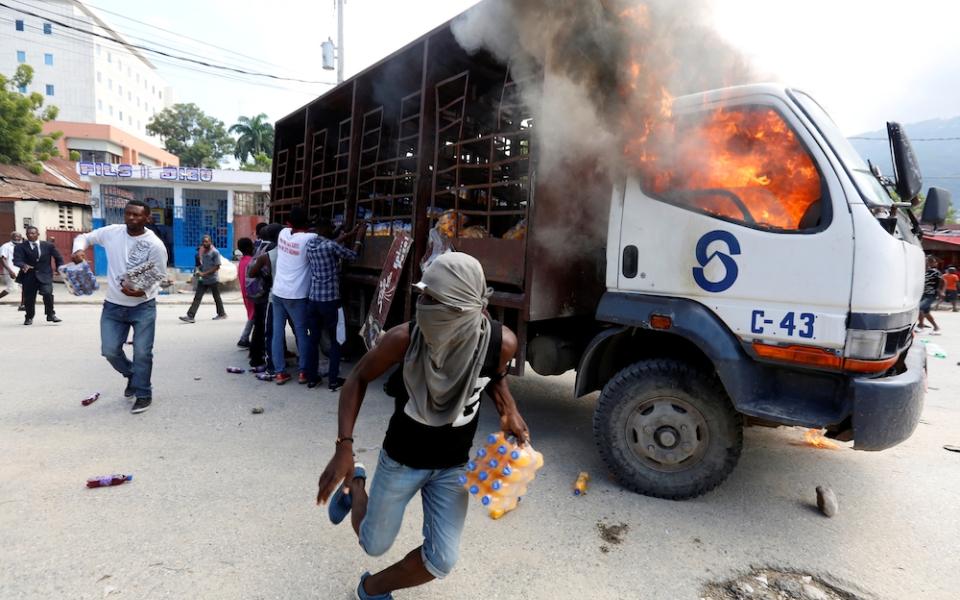Demonstrators loot a burning truck after deadly protests to demand the resignation of Haitian President Jovenel Moise in Port-Au-Prince Nov. 19, 2019. (CNS/Reuters/Jeanty Junior Augustin)
