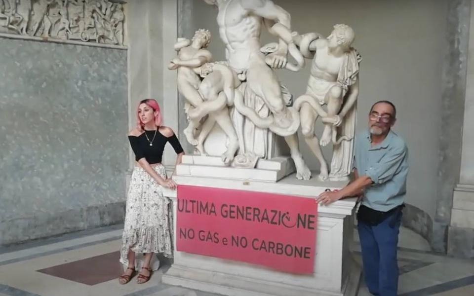 A video grab from footage made available by environmental activists shows two members of Ultima Generazione glued their hands on the Roman statue of Laocoön and His Sons at the Vatican Museums to protest climate change. (Ultima Generazione Via AP)