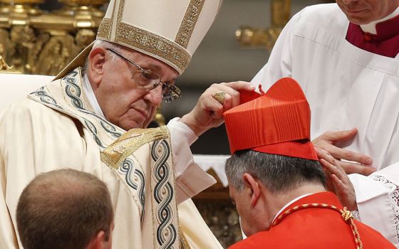 In St. Peter's Basilica at the Vatican in 2018, Pope Francis place a red biretta on Cardinal Giovanni Angelo Becciu, then Vatican substitute secretary of state, during a consistory at which Becciu and 13 others became cardinals. (CNS/Paul Haring)