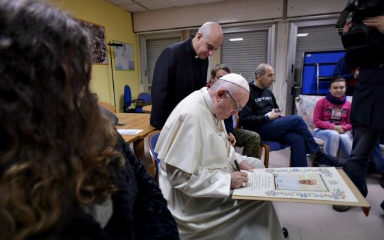 Pope Francis signs a papal blessing as he visits mentally disabled people at Il Ponte e l'Albero community on the outskirts of Rome Dec. 7, 2018. (CNS/Vatican Media) 