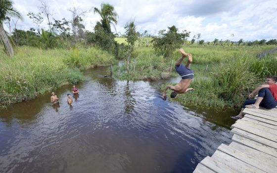 Children jump from a rickety bridge into a river near Anapu, Brazil, where deforestation and land grabbing for large-scale agriculture are endangering the livelihoods — and lives — of small farmers. Faith leaders have called for personal conversion and ec