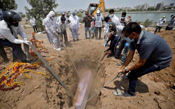 People lower the body of a man who died of COVID-19 into a grave at a cemetery May 3 in Ahmedabad, India. (CNS/Amit Dave, Reuters)