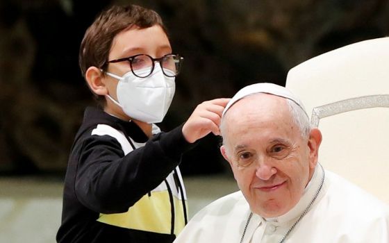 Ten-year-old Paolo touches Pope Francis' zucchetto after spontaneously walking onto the stage during the weekly general audience at the Vatican Oct. 20. (CNS/Reuters/Remo Casilli)