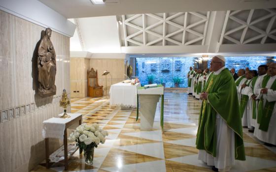 Pope Francis, wearing a green vestment, stands in front of a reliquary and sculpture of the Madonna and child
