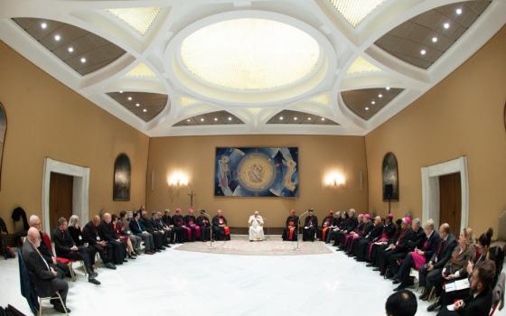 Pope Francis, seated, presides over large meeting