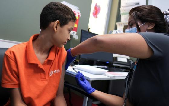 Young boy receives vaccine in arm from nurse