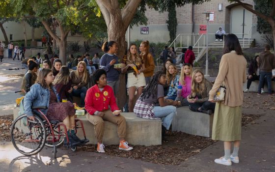 Teens sitting outside in high school courtyard, scene from movie "Moxie"