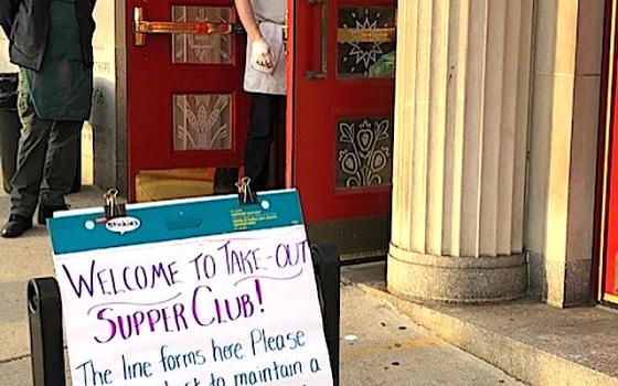 Sidewalk sign inviting homeless diners to a free take-out dinner at the Paulist Center in Boston (Susan Rutkowski)