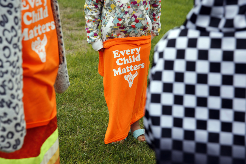 A Red Cloud Indian School student holds an orange T-shirt at an assembly for Orange Shirt Day on Sept. 30, 2021, in Pine Ridge, S.D. (AP/Emily Leshner)