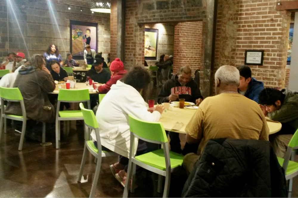 People enjoy dinner at Bishop Sullivan Center's One City Café, a restaurant-style community kitchen offering free meals in Kansas City, Missouri, as volunteers and staff serve them Feb. 26. (NCR photo/Maria Benevento)